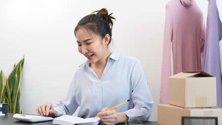 Live shopping concept a female seller counting a stock and checking a number of parcels before sending to customers by postal delivery.の写真素材