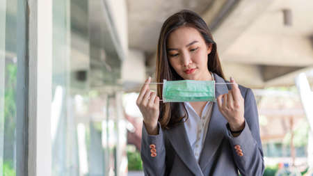 Working woman concept a working woman preparing herself before meeting the client by wearing the disposable face mask to protect herself from the corona virus.の写真素材