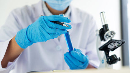 scientists researching in laboratory in white lab coat, gloves analysing, looking at test tubes...