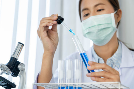 Scientist wear lab coat and protective wear are working with research or doing investigations with test tubes in experiment, Laboratory and development concept.の写真素材