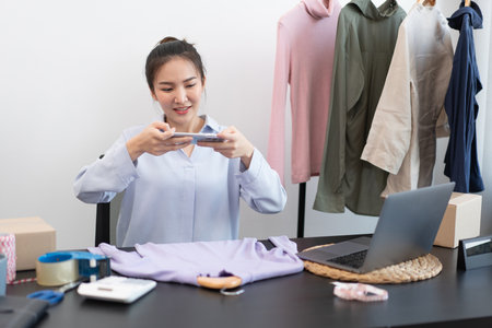 Live shopping concept a female online seller taking a photo of a cloth which is a product in her online shop.の写真素材