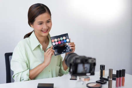 A female beauty blogger reviewing quality of the colorful eyeshadow palette as a new arrival product.の写真素材