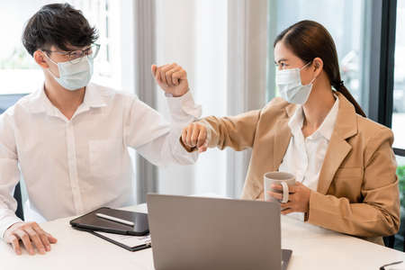 two business partners wearing protective mask touching elbows together agreed to work on the new project.の写真素材