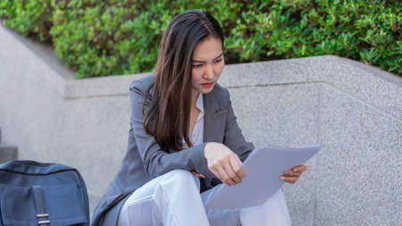 Working woman concept a woman sitting on the step looking at the job applications with feeling anxious and desperate.の写真素材