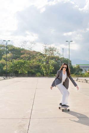 Working woman concept a woman with long hair wearing the smart suit playing the skateboard professionally.の写真素材