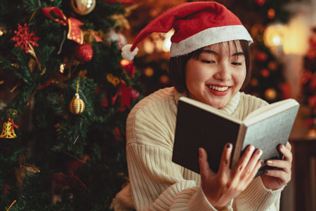 a young Woman in front of Christmas tree reading a book at home with x-mas decoration