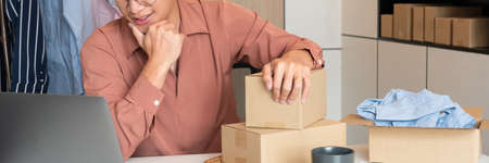 Asian business owner working at home with packing box of his online store prepare to deliver products to customers, alpha generation life style conceptの写真素材