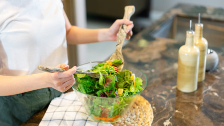 salad concept the woman with white t-shirt and dark green pants standing at the kitchen and making a...