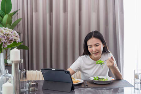 salad concept the lady having Caesar salad and slices of toasted bread while having a video call with someoneの写真素材