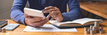 saving concept The male money saver attempting to count his income this month and other past old months by using a calculator.の写真素材