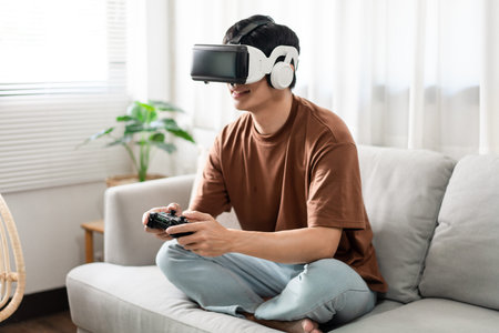 Technology Concept A person wearing a virtual reality headset and holding a black console game while...