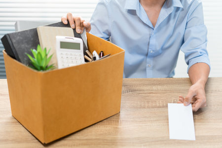 Resignation Concept The male officer sitting, putting his box of his belongs on the desk and handing...