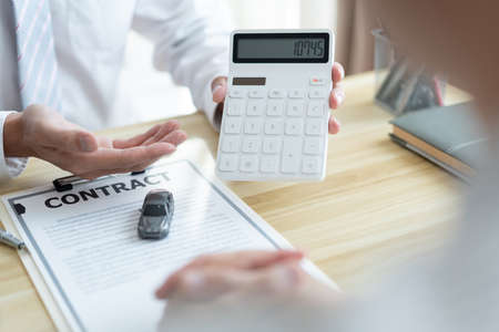 The selling agent informing his client about the expense by showing it on the calculator.の写真素材