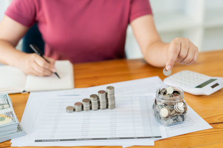 Saving concept the woman putting the coins into the bottle and taking note the amount of money.
