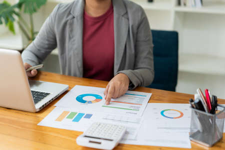 Business analyst concept the data analyst holding and pointing her pen at the document about sale chart.の写真素材