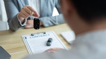 Insurance concept the car dealer explaining the conditions of the car while showing a car key to his client.の写真素材