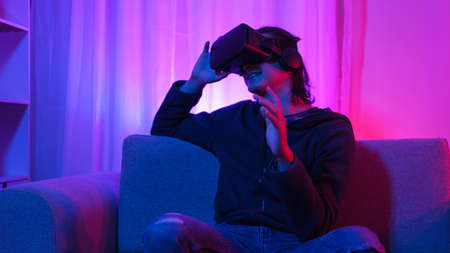 Metaverse technology concept, Man holding VR goggles and pointing to touch experience in metaverse.の写真素材