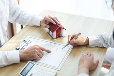 Insurance concept the realtor pointing out the place to sign the customerâs name on the paper.の写真素材