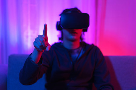 Metaverse technology concept, Man wear VR goggles and pointing to touch experience in virtual world.