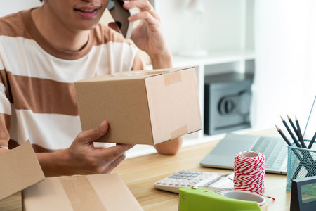 Online shopping concept a retailer holding a parcel post while talking with his customer on the...