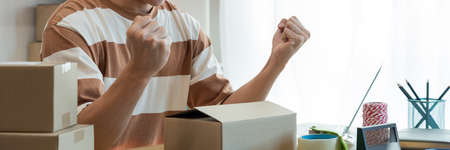 Online shopping concept the online salesperson having cheerful facial expression while setting his goods into the box.の写真素材