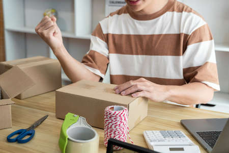 Online shopping concept the online salesperson having cheerful facial expression while setting his goods into the box.の写真素材