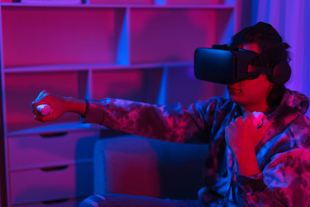 Metaverse technology concept, Man wear VR goggles and have fun to play boxing game in virtual world.の写真素材