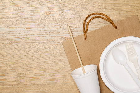 Eco friendly concept, Paper bag plate cutlery and cup with straws on wooden background.