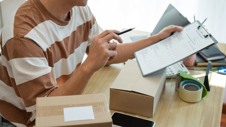 Online shopping concept the selling agent writing down a product report and checking his product in the parcel.の写真素材