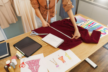 Fashion design concept, Asian female designer use tape measure on fabric to make sewing new dress.