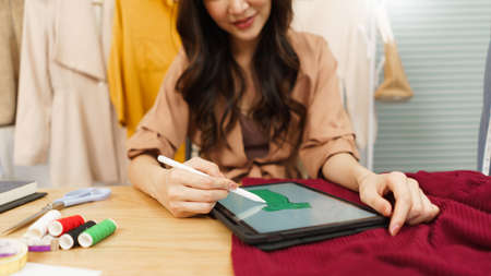Fashion design concept, Asian female fashion designer use tablet to drawing new dress collection.の写真素材
