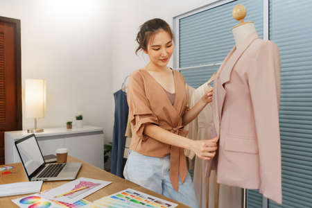 Fashion design concept, Asian female tailor is checking quality completeness of suit on mannequin.の写真素材
