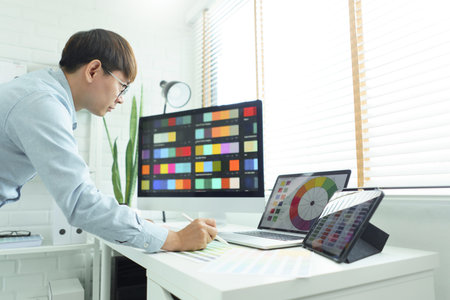 Creativity concept, Male graphic designer choosing color swatch samples on document and designing.