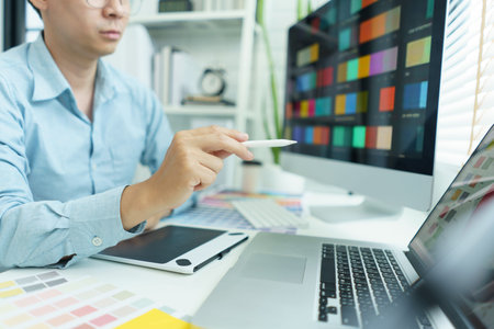 Creativity concept, Male graphic designer pointing color swatch samples and drawing on tablet.