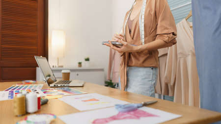 Fashion design concept, Asian female designer thinking new collection and sketching on notebook.の写真素材