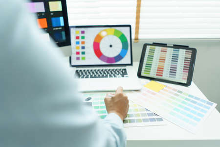 Creativity concept, Male graphic designer choosing color swatch samples on document and designing.の写真素材