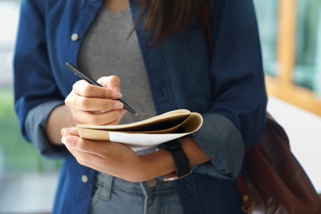 Education and literacy concept, College student girl thoughtful and taking note on notebook.