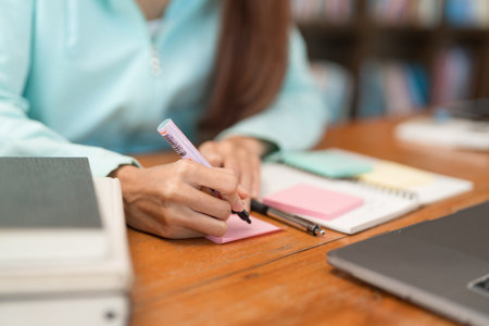 College education concept, Teenage girl is writing 
vocabulary on sticky note while study tutorial.