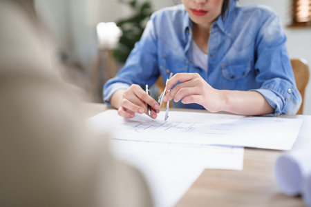 Concept of engineering consulting, Two female engineers brainstorming sketches blueprint together.
