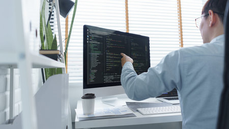 Software development concept, Male programmer checking data codes on document and computer screen.