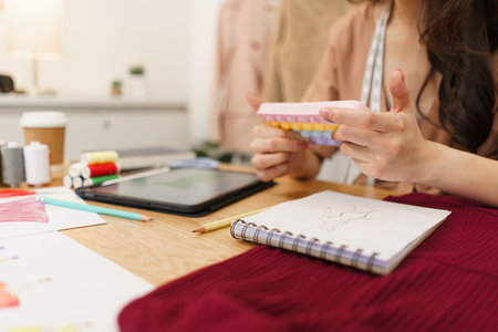 Fashion design concept, Asian female tailor use phone to searching data for new clothes collection.の写真素材