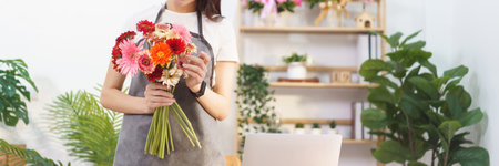 Flower shop concept, Female florist holding colorful gerbera to prepare for making flower bouquets.の写真素材