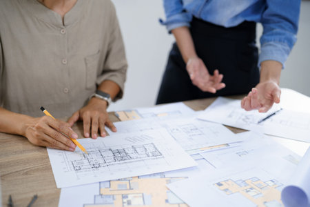 Concept of engineering consulting, Two female engineers discussing about blueprint of condominium.