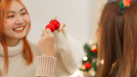 Christmas decoration concept, Two women wears reindeer horns and holds red ball with happiness.の写真素材