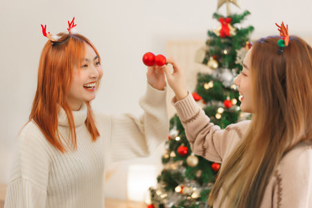 Christmas festive concept, Two women wears reindeer horns and holds christmas ball with happiness.の写真素材
