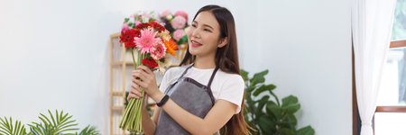 Florist concept, Female florist holds colorful gerbera to prepare for making flower bouquet in shop.の写真素材
