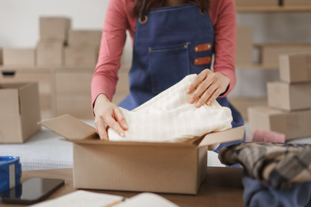 Close up of a young woman packing a product into a cardboard boxの写真素材