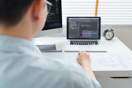 Programmer working on computer at home office. Programmer programming code on laptop.の写真素材