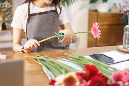 Flower shop concept, Female florist cutting gerbera with scissor to prepare for making flower vase.の写真素材