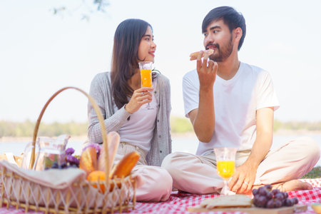 Young couple in love looking into each other eyes while drinking orange juice and eating bread.の写真素材
